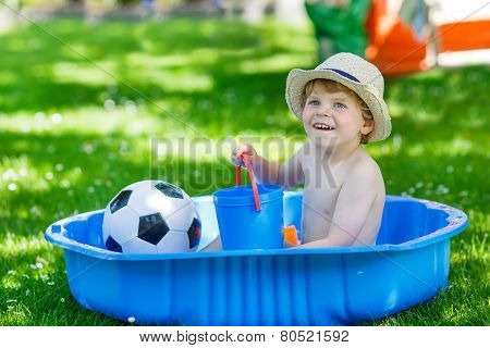 Little Toddler Boy Having Fun With Splashing Water In Summer Garden Pool.