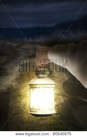 Right Hand Holding Light Illuminating Dark Road At Night