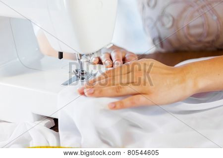 Close up of woman dressmaker hands working with sewing machine