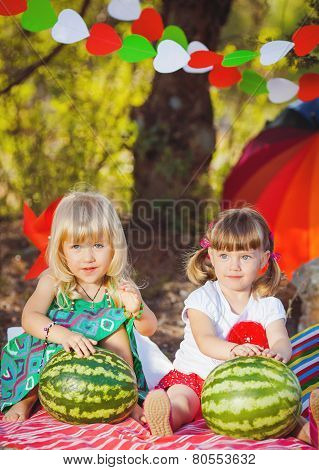 Two little girlfriends in the summer at the cottage after harvest watermelons.