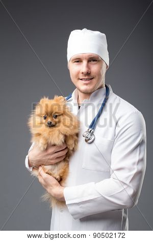 Smiling Male Vet With Phonendoscope Holding Cute Pomeranian Dog