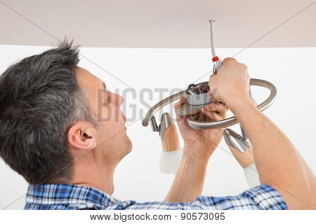 Electrician Fixing Light On Ceiling