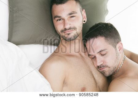 A homosexual couple onder a bed in studio white