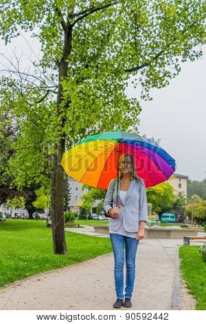 a young woman walks with a colorful umbrella in his hand walking in the rain.