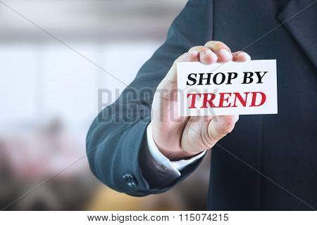Businessman holding a white sign with the message shop by trend.
