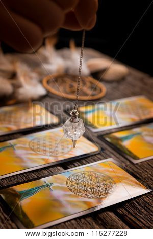 Fortune teller holding a pendulum over tarot cards