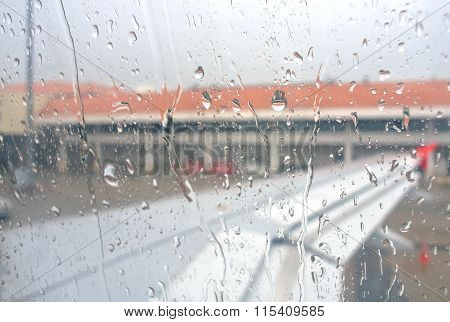 Drops Of Rain On Glass Window Of Airplane At Airport Background