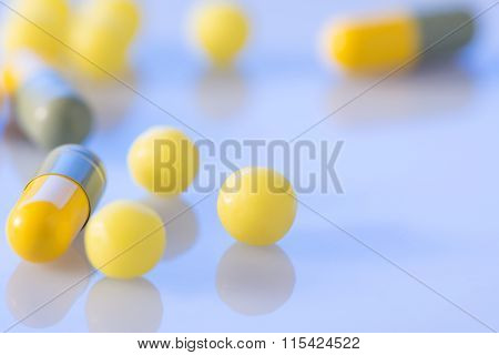 Coloured pills of different shape on the surface.