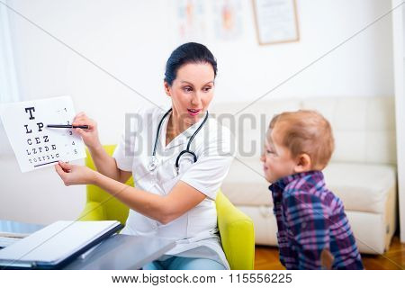 Female pediatrician pointing at eye chart to child