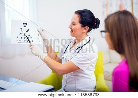 Female pediatrician pointing at eye chart to child