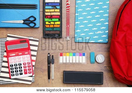 School set with backpack and supplies on wooden background