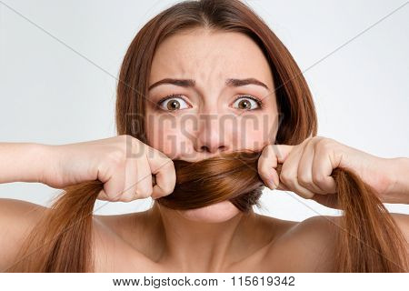Closeup portrait of scared frightened young woman covered her mouth with her long hair over white background