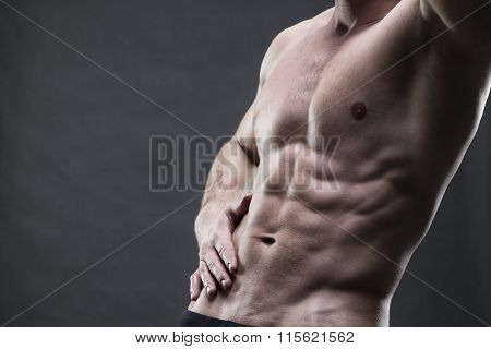 Handsome Muscular Bodybuilder Posing On Gray Background. Low Key Studio Shot With Copy Space