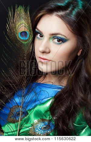 Close Up Beauty Portrait Of Beautiful Girl With Peacock Feather. Creative Makeup Peafowl Feathers