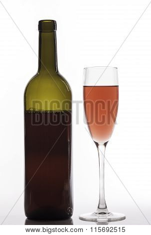 glass of pink wine and bottle on white background