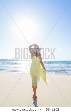 Woman walking on the trpical  beach in yellow dress