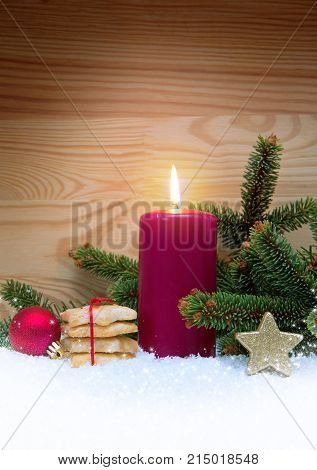 Avent candle and Christmas cookies isolated on wood background. Christmas background with snow, candle and fir-tree branch.