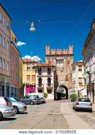 Rovigo - July 2017, Veneto region, Italy: View of the old tower with arch, surrounding buildings and parked cars