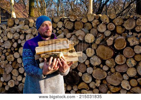 The woodcutter holds firewood in hand. Portrait of woodcutter.