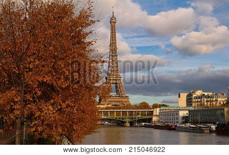 Color fall image of the Eiffel tower in Paris, France, Europe, on a sunny autumn day with blue sky and colorful leaves .