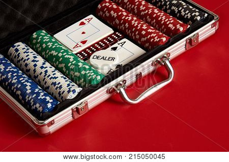 Poker set in metal suitcase. Risky entertainment of gambling. Top view on red background. Casino background. Copy space. Still life.