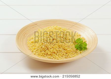 plate of uncooked alphabet pasta on white wooden background