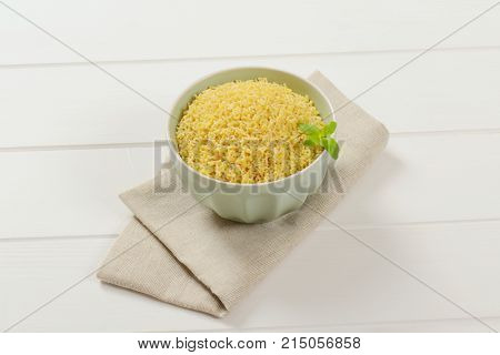 bowl of uncooked alphabet pasta on beige place mat