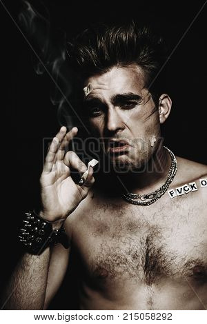 Antisocial behavior, bad habits. Portrait of a bad boy smoking cigarette. Rocker, punk.
