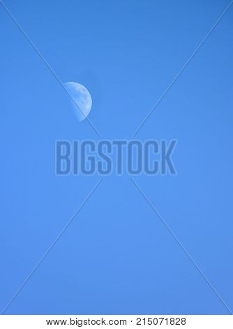 Half moon on blue sky background during daytime.