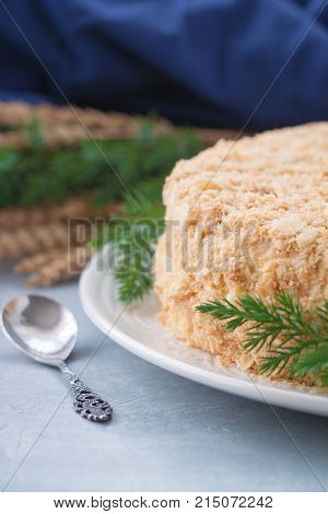 Round multi-layered cake Napoleon with custard on a light-blue table background. Selective focus. Toned.