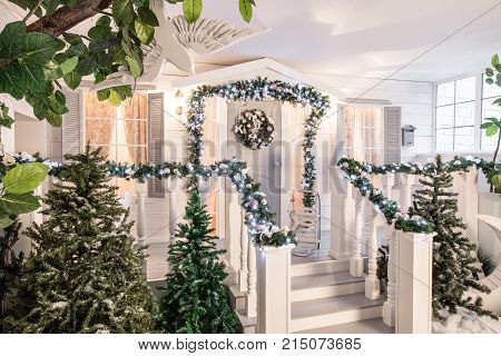 house entrance decorated for holidays. Christmas decoration. garland of fir tree branches and lights on the railing.