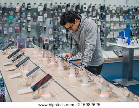 Closeup view of male customer choosing digital tablet in the mobile phone shop. difficult decision. Various choice