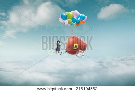Happy sister enjoy with fantasy apple cycle ride and floating in sky with bunch of colorful balloons .