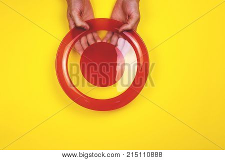A man holding a red empty plate on yellow background