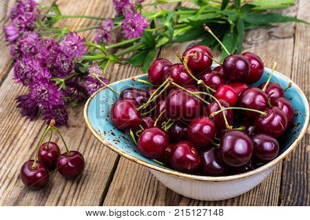 Mellow sweet cherry in bowl on wooden table. Studio Photo