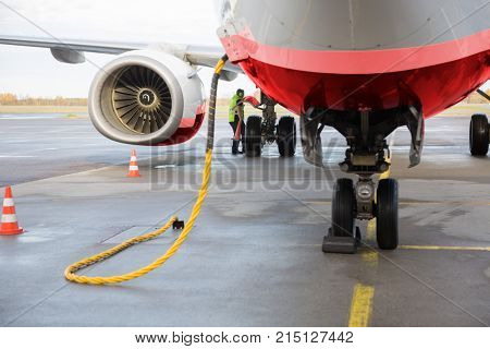 Airplane Being Charged While Worker Working On Runway