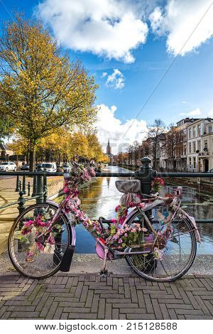 Abandoned Decorated And Rusty Pink Bicycle Attached To The Ramp Of Amsterdam Canal Bridge During Aut