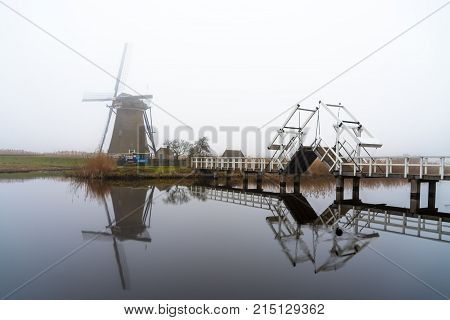Kinderdijk Windmill View From The Bridge Over The Calm Canal Water Netherlands