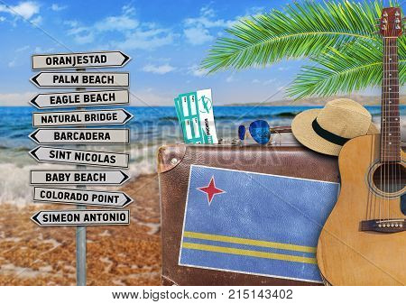 Concept of summer traveling with old suitcase and Aruba town sign