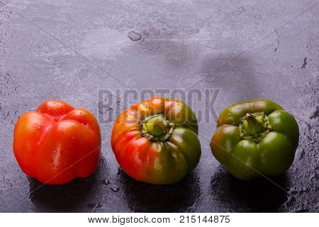 Appetizing, juicy, Bulgarian pepper, decomposed orange and green, mature, and half-ripe, on a black background. Top view, free space for text.
