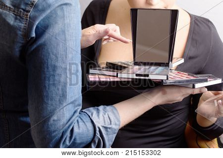 Make-up Artist And Model Choose The Color And Tone Of Cosmetics. A Make-up Palette In The Hands Of A