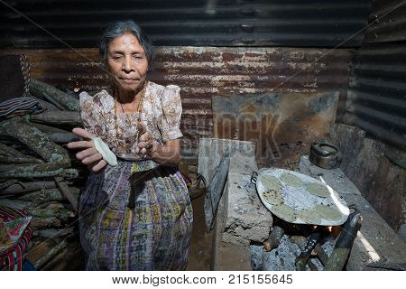 April 2, 2016 San Pedro la Laguna, Guatemala: an elderly tzutujil mayan woman is flattening tortillas in her palms beside wood fire
