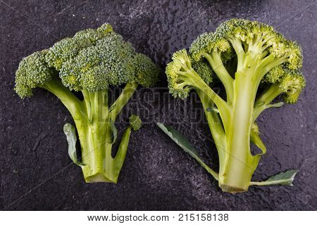 Fresh, appetizing, green broccoli, cut in half on a dark background, top view