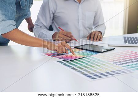 Young colleagues designers working together on a creative project and color samples for selection Color swatch samples Brainstorming Planning Partnership creative graphic design working desktop.