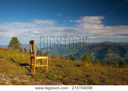 Old wooden chair on the top in Carnic Apls in Austria.View of the mountains in Slovenia.