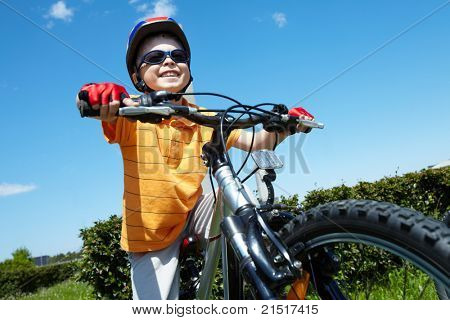 Portrait d'enfant heureux à vélo contre le ciel bleu