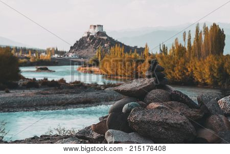Stone stupa foreground with Stakna Gompa and Indus river before sunset with cloudy sky and mountains background