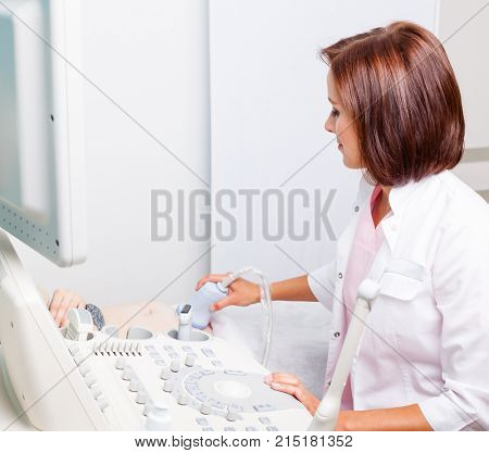 Close-up shot of sonographer scanning young pregnant woman's belly with ultrasonic transducer doing obstetric ultrasonography