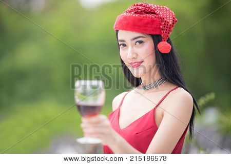 Beautiful woman with a glass of red wine againt blurred party background.Red wine Christmas party concept. Happy new year coming soon.