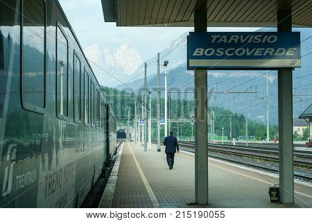 TARVISIO BOSCOVERDE ITALY - MAY 30 2008: Man walking on the platform of Tariviso Boscoverde train station with an overnight train and its passenger cars waiting on the left